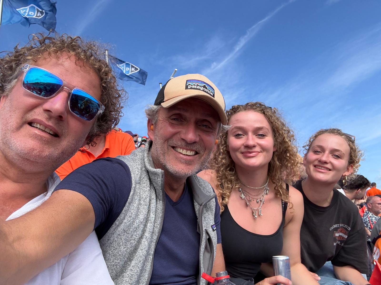 A group selfie in a Formula 1 grandstand under a blue sky