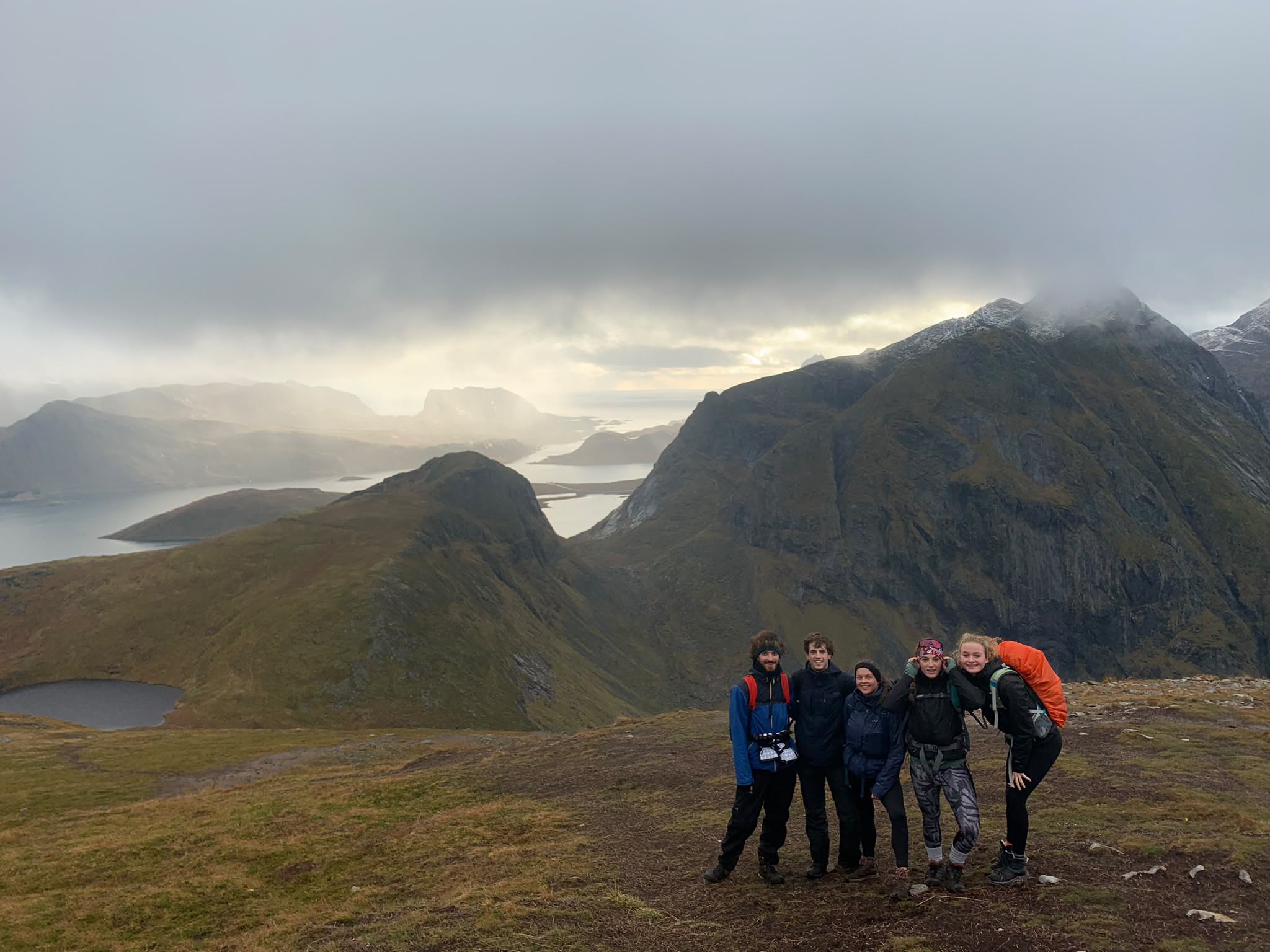 A group of hikers on a mountain ridge with lakes and peaks in the background